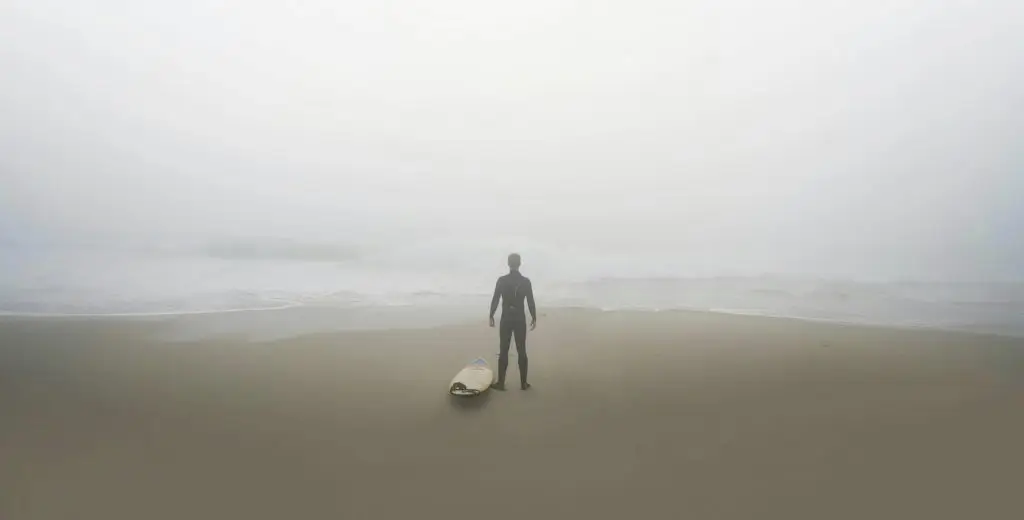 Surfer på strand i tåge