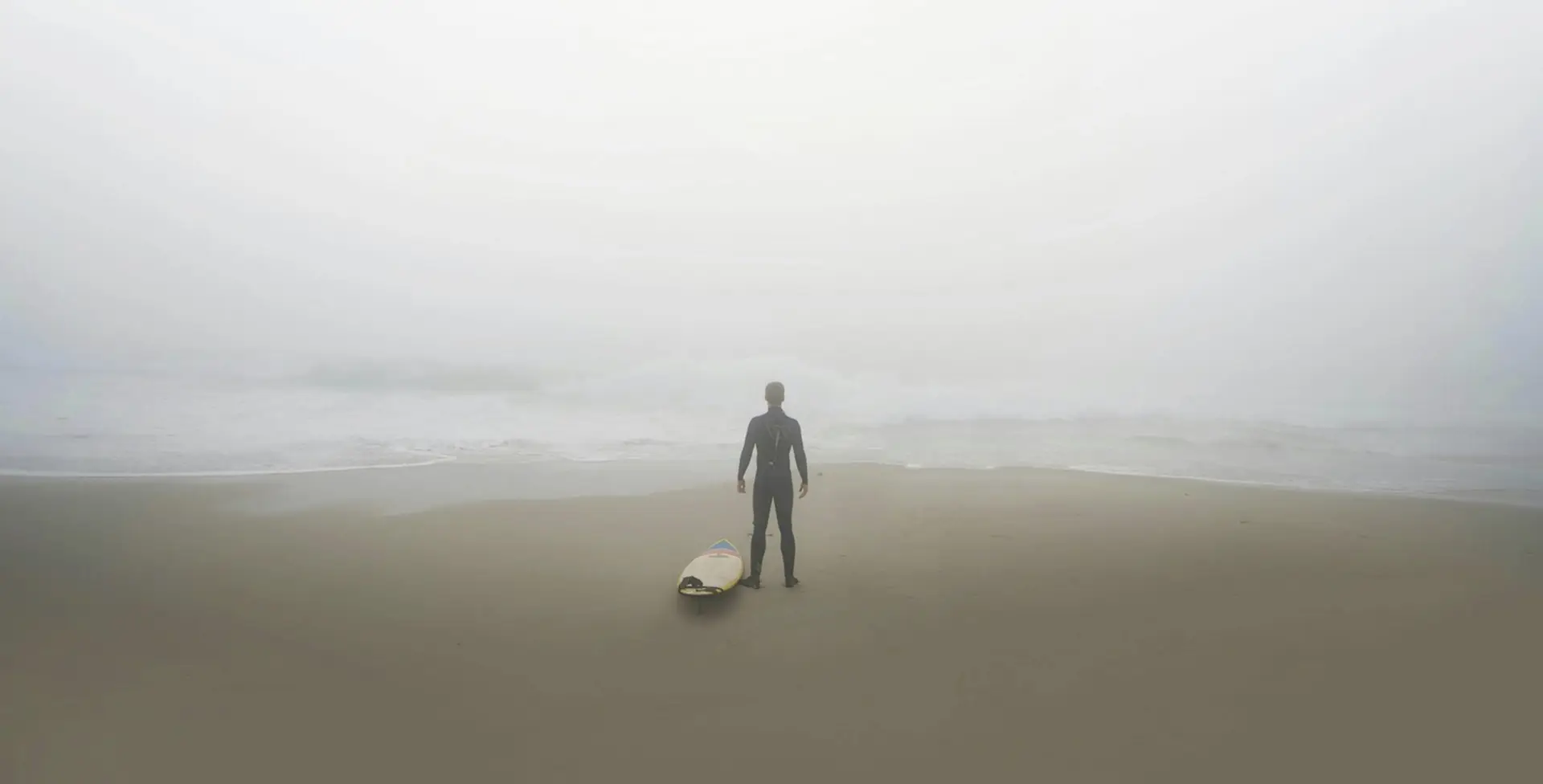 Surfer på strand i tåge